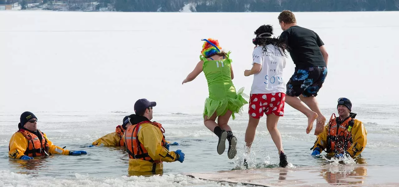 group of people jumping into icy water