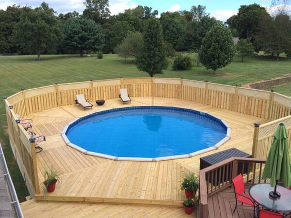 Awesome round above ground pool with wood deck and fence surrounding it