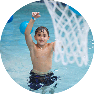 young boy playing basketball in the pool